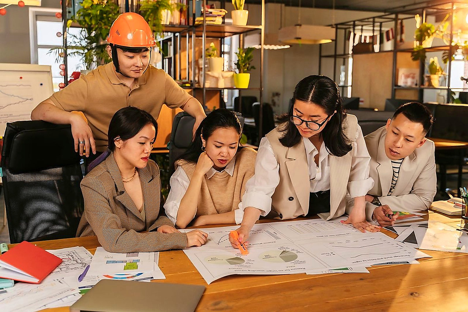 Free A diverse team of professionals working together on architectural plans in a modern office setting. Stock Photo