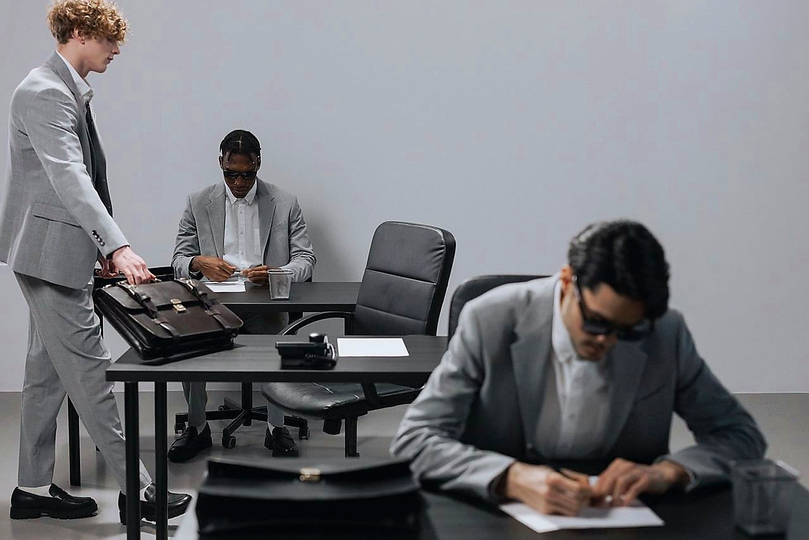 Free Business office with diverse employees in gray suits working at desks in an indoor setting. Stock Photo