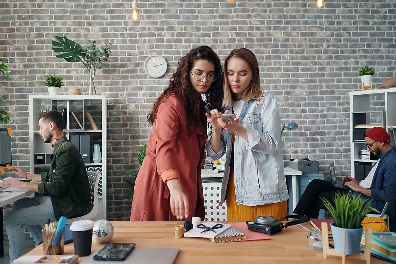 Free Collaborative team of men and women in a modern office workspace working on creative design projects. Stock Photo