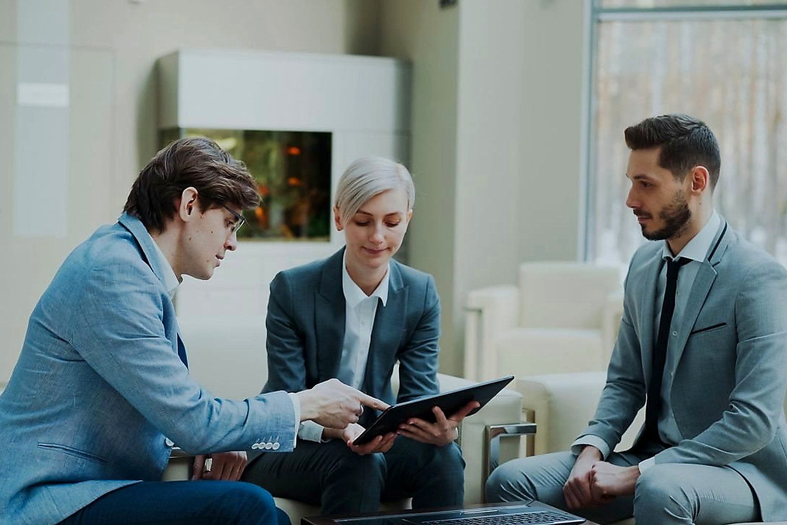 Free Three professionals engaging in a business meeting in a modern office setting. Stock Photo