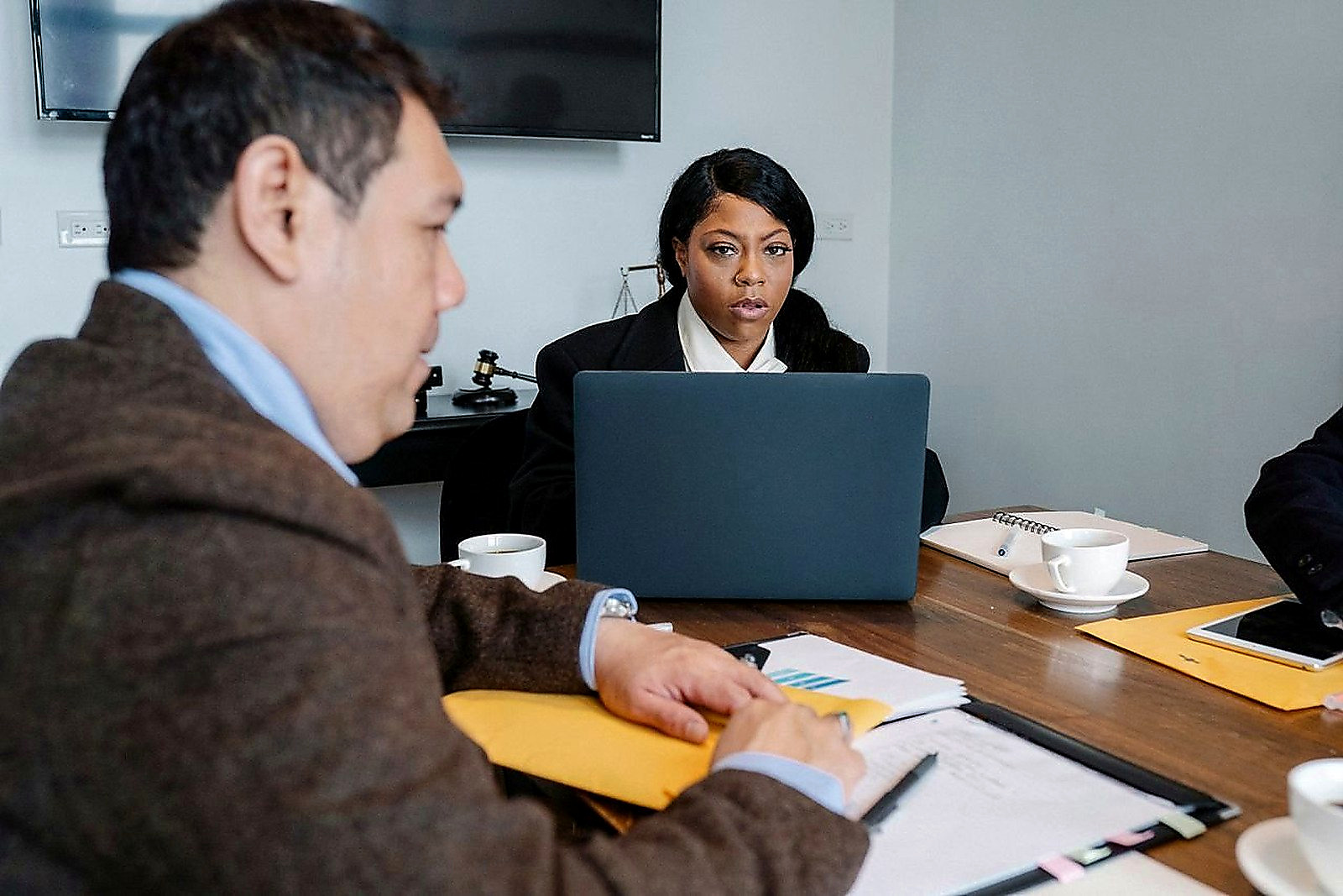 Free Group of multiethnic coworkers in formal wear sitting at table with laptop and documents while discussing business issues Stock Photo